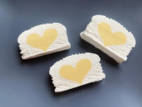 Rectangles of vanilla ice cream with yellow mango hearts on a gray background Stock Photos