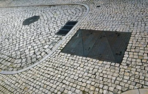 Rectangular and round hatches and grid of urban communications on the cobbles Stock Photos