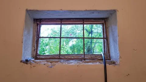 A rectangular basement window is tightened with a metal mesh and a grill. Tec Foto stock