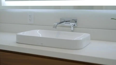 Rectangular bathroom sink with sleek faucet mounted on wall above it. White Stock Footage 276026667
