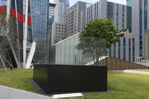 The rectangular black box-shaped glass structure stands on the lawn in fron.. Stock Photos