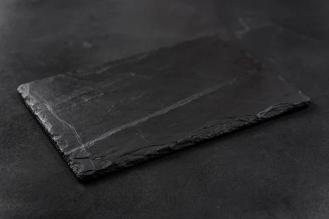 Rectangular black cheese board on a dark background Photos