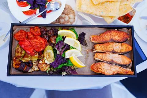 Rectangular black dish with grilled fish and vegetables. Foto stock