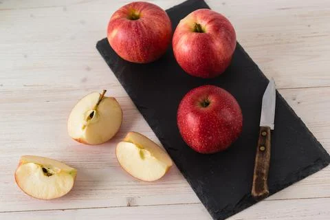 In a rectangular black dish on white wooden table are three juicy beautiful r Stock-Fotos
