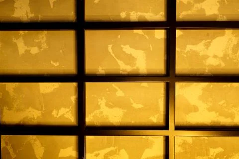 Rectangular black metal grill on the wall, with a golden background. 스톡 사진