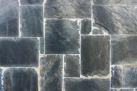Rectangular black stones wall with dirty joins. Background texture. Wide angl Stock Photos