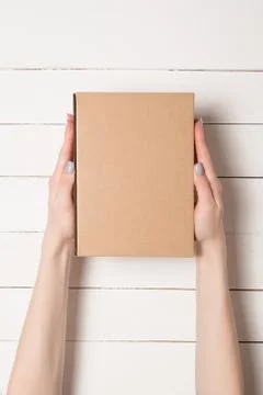 Rectangular box in female hands. Top view. White table on the background 스톡 사진