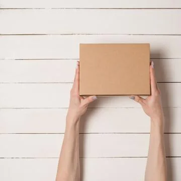 Rectangular box in female hands. Top view. White table on the background 스톡 사진