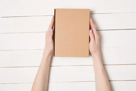 Rectangular box in female hands. Top view. White table on the background 写真素材