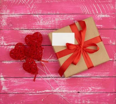 Rectangular box with a gift tied with a red silk ribbon and red hearts Stockfoto's