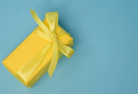Rectangular box with a gift wrapped in yellow paper and tied with a silk yell Stockfoto's