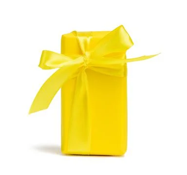 Rectangular box with a gift wrapped in yellow paper and tied with a silk yell Stock Photos
