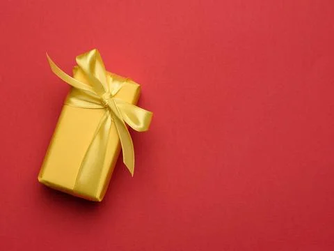 Rectangular box with a gift wrapped in yellow paper and tied with a silk y... Stock Photos