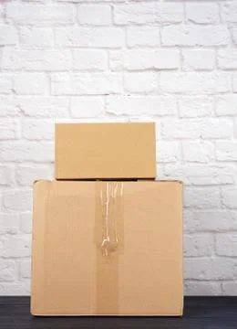 Rectangular box made of brown corrugated cardboard on a white brick wall back Stockfoto's