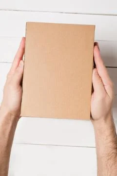 Rectangular box in male hands. Top view. White table on the background 写真素材