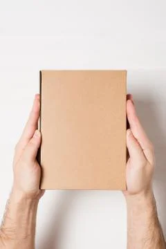 Rectangular box in male hands. Top view. White table on the background Stock Photos