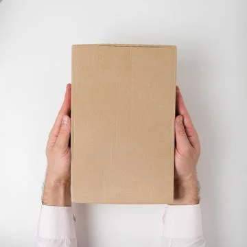 Rectangular box on men's hands on white background. Top view. Vertical frame Stock Photos