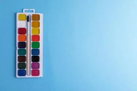 Rectangular box palette with honey colored watercolors and a brush on a blue Stock Photos