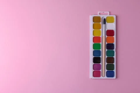 Rectangular box palette with honey colored watercolors and a brush on a pink Stock Photos