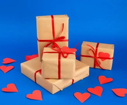 Rectangular box is wrapped in brown paper and tied with a red thin silk ribbo Stock Photos