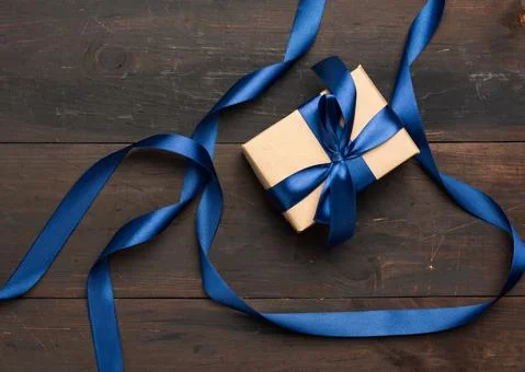 Rectangular box wrapped in brown paper and tied with a blue silk ribbon with  Stock Photos