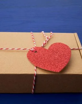 Rectangular brown box with a gift and a red paper heart tied to a rope Stockfoto's