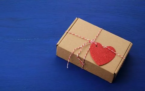 Rectangular brown box with a gift and a red paper heart tied to a rope rec... Stockfoto's