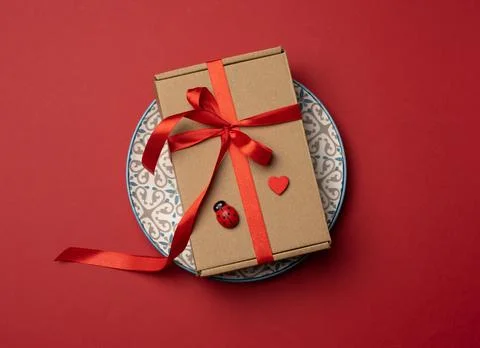 Rectangular brown cardboard box tied with a silk red ribbon lies in a round c Foto stock