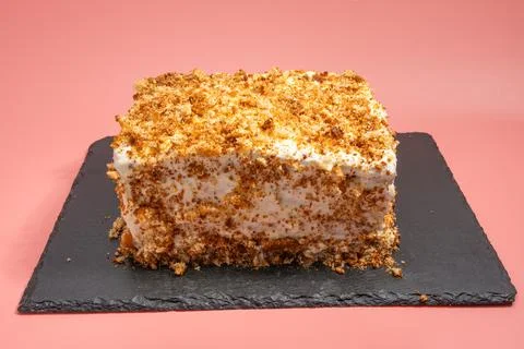 Rectangular cake with whipped cream and crumb decoration on a black slate plate. Stockfoto's