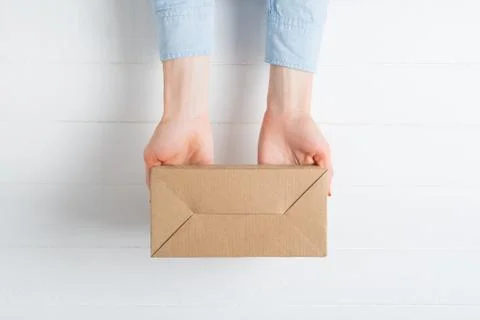 Rectangular cardboard box in female hands. Top view, white background 写真素材