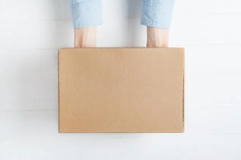 Rectangular cardboard box in female hands. Top view, white background Stockfoto's