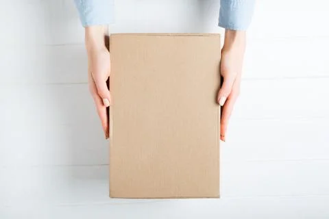 Rectangular cardboard box in female hands. Top view, white background 스톡 사진