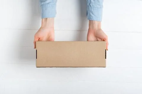 Rectangular cardboard box in female hands. Top view, white background 写真素材