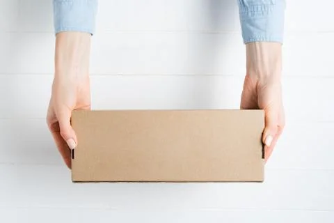 Rectangular cardboard box in female hands. Top view, white background Stockfoto's