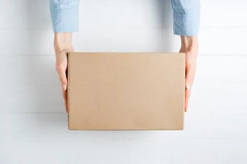 Rectangular cardboard box in female hands. Top view, white background 스톡 사진