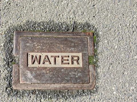 Rectangular cast iron pavement plate marked WATER Stock Photos