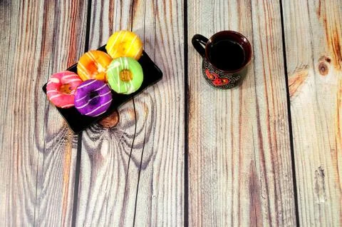 A rectangular ceramic black plate with five donuts in multi-colored glaze and Stock Photos