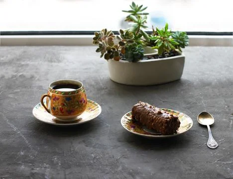 A rectangular chocolate cake and a cup of coffee on a gray dark table Stock Photos