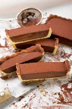 Rectangular chocolate tart with cocoa powder, partly sliced 스톡 사진