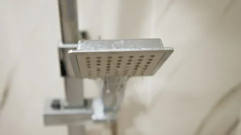 Rectangular chrome shower head releasing steady water streams from underside in Stock Footage 343543327