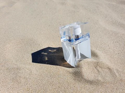 Rectangular clear glass perfume bottle on beach sand with trendy shadow Stock Photos