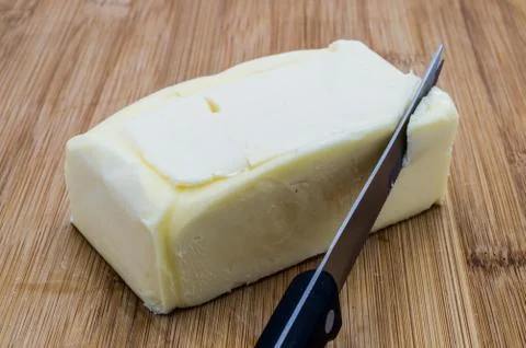 Rectangular clod of butter with a black knife 库存照片