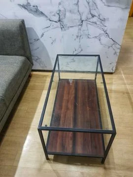 A rectangular coffee table featuring a glass top and a dark wood interior sit Fotos Stock
