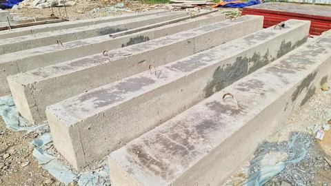 Rectangular concrete beams with metal lifting loops are prepared at a constru Foto stock