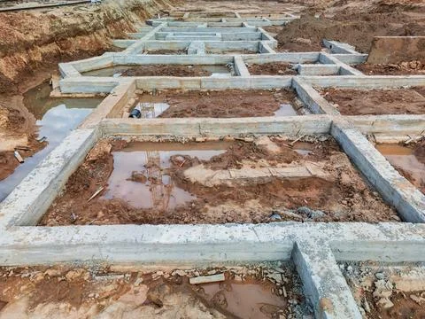Rectangular concrete foundations sit underwater in the excavation, marking co Stock Photos