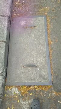 Rectangular concrete manhole cover with iron handles on urban pavement with.. Fotos de archivo