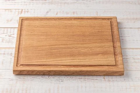 Rectangular cutting board with edging on a white wooden table. mockup of a fo 写真素材