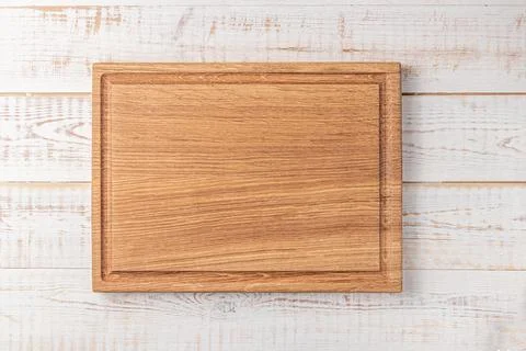 Rectangular cutting board with edging on a white wooden table. mockup of a fo Stock Photos