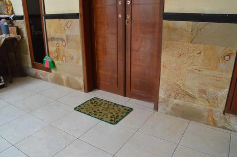 A Rectangular Doormat With A Leaf Pattern Placed On A Tiled Floor Near A Wo.. Foto stock