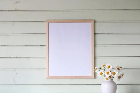Rectangular empty picture frame hangs on a light green board wall above a Foto stock